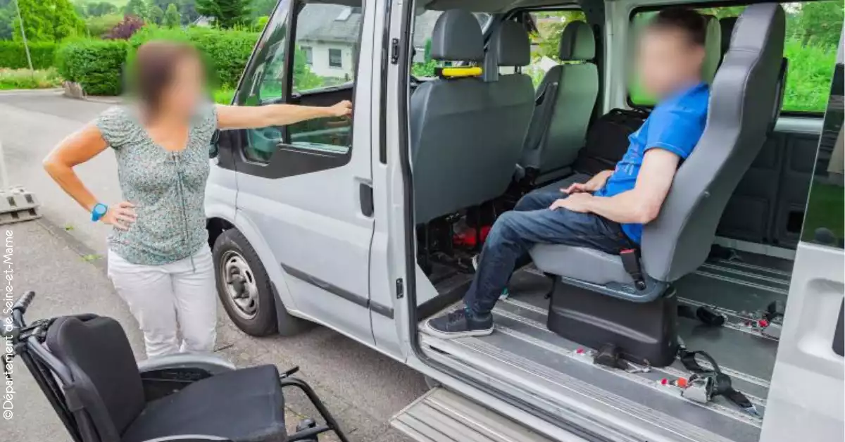 Une femme accompagnée d'un élève en situation de handicap dans un bus adapté.